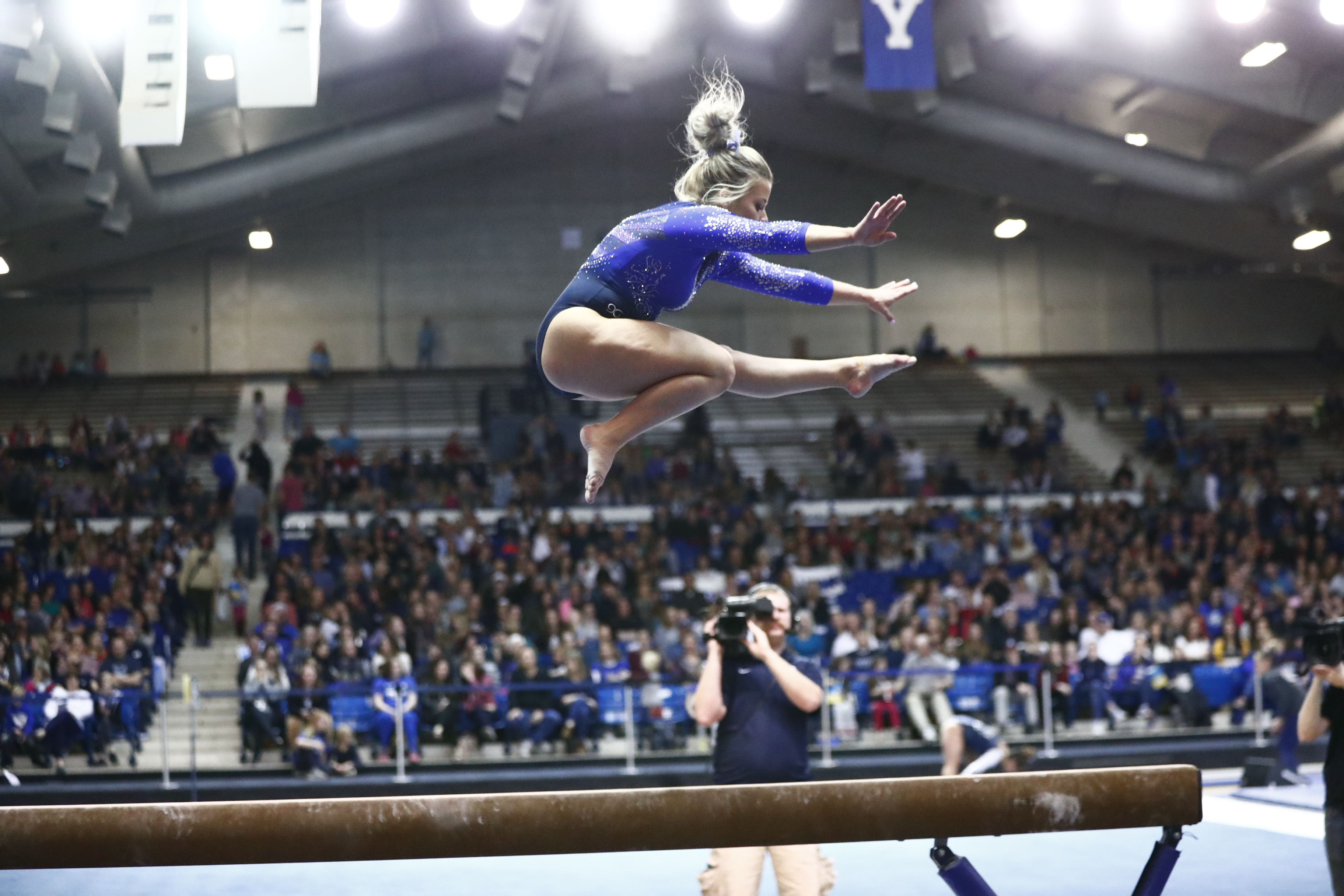 gymnast jumps on beam in front of crowd
